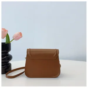 Close-up of a brown leather saddle bag with gold hardware and adjustable strap