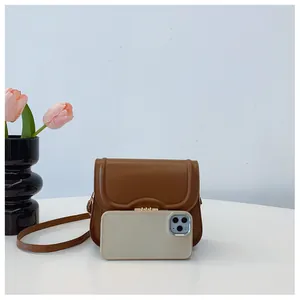 Brown leather crossbody bag with wave-edge flap and gold lock shown next to a smartphone