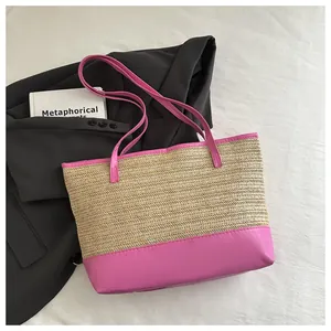 Detail view of pink leather trim and straw woven texture on a casual summer tote bag