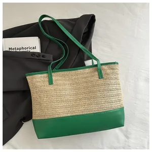 Detail of woven straw tote bag with vibrant green leather trim and contrast stitching