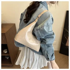 Beige glanzende hobo-tas gedragen door model met spijkerjasje in een zijwaartse blik
