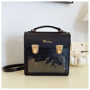 Close-up of black crossbody bag with gold Mudnag logo and a transparent front window