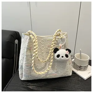 Detail of white quilted tote bag with floral embroidery and cute panda plush keychain