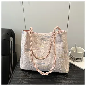 Detail of pink quilted tote bag with wave embroidery and woven leather handles