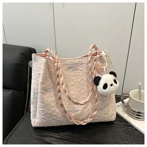 Detail of pink jacquard tote bag with woven handles and cute panda plush keychain charm