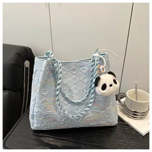 Close-up of light blue bubble textured tote bag with embroidery and panda charm