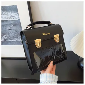 Detail of black faux leather tote featuring a clear PVC window and gold vintage buckles
