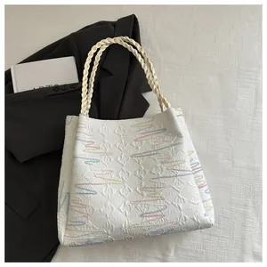 Detail of white tote bag featuring embossed rhombus texture and colorful wavy embroidery