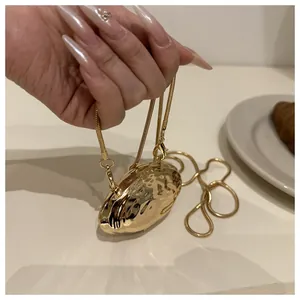 Detail of a mini golden shell bag with hammered metal texture and snake chain strap