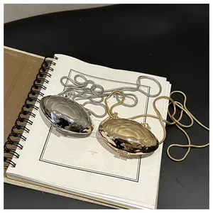 Detail view of mini shell purses in gold and silver with wavy texture and snake chains