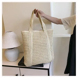 Detail of the woven hollow texture and spacious handle on this beige straw tote bag