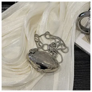 Detail of silver metallic shell bag with molten lava texture and delicate chain strap