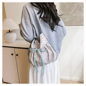 Detail view of floral drawstring shoulder bag with blue checkered bow on white canvas
