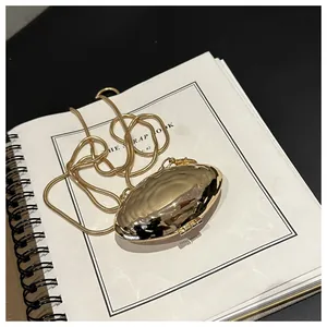 Macro detail of a gold metallic shell clutch with water ripple texture and snake chain