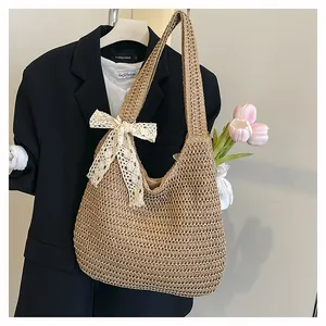 Détail du sac bandoulière en paille kaki avec tissage ajouré et nœud en dentelle blanche