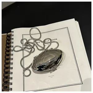 Detail of silver metallic mini shell bag with water ripple texture on a notebook