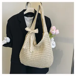 Détail d'un cabas tressé beige avec nœud en dentelle suspendu sur présentoir épuré