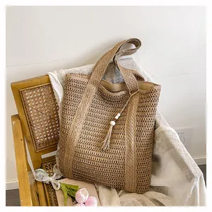Detail of woven straw tote bag with beaded tassel charm and soft fabric lining
