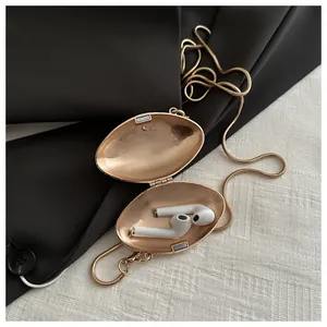 Detailed view of a gold metallic shell clutch with a crossbody chain on fabric