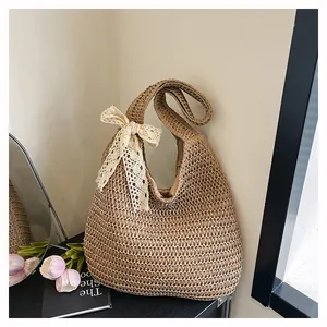 Détail d'un sac à main en paille tressée avec un nœud en dentelle crème et doublure