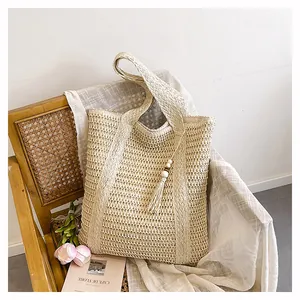 Detail of hollow woven straw tote bag with white bead tassel on a vintage chair