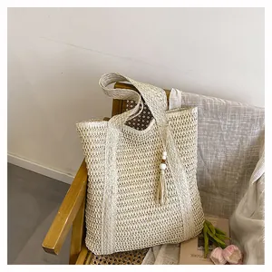 Close-up of beige woven tote bag with white bead tassel on a vintage rattan chair