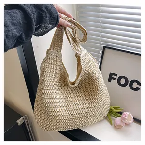 Détail du sac à bandoulière en paille tissé à la main avec doublure claire et texture souple