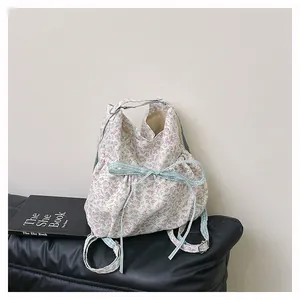 Close-up of floral canvas backpack featuring a light blue plaid bow and adjustable straps