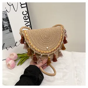 Détail du sac de selle tissé bohème avec broderie dorée et pompons colorés