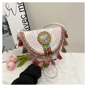 Détail d'un sac besace en paille bohème avec franges colorées et broderies perlées