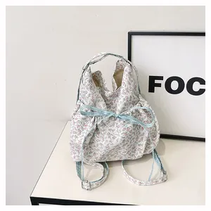 Floral print canvas bag featuring drawstring closure and adjustable blue shoulder straps