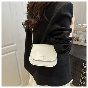 Close-up of white leather shoulder bag with Fashion Trend engraving shown on a model