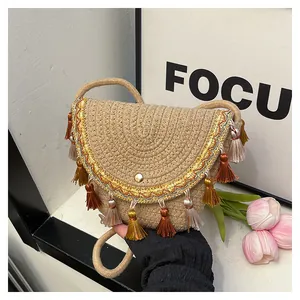 Détails d'un sac besace tissé avec broderies colorées et pompons de style bohème