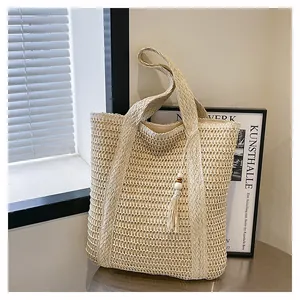Detailed close-up of woven beige tote bag featuring hollow texture and tassel wood bead charm