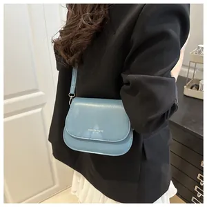 Detail of blue leather crossbody bag with white fashion trend text logo and silver hardware