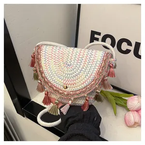 Détail d'un sac selle bohème avec coutures colorées, pompons et texture tissée