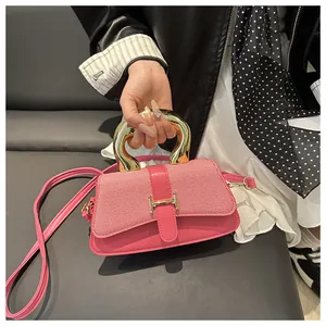 Detail of pink fashion handbag with large gold round handle and metallic H buckle