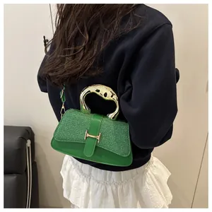Detail of green crossbody bag with textured glitter flap and golden H-shaped clasp