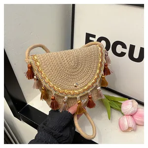 Détail du sac besace en paille tressée avec glands colorés et broderie dorée