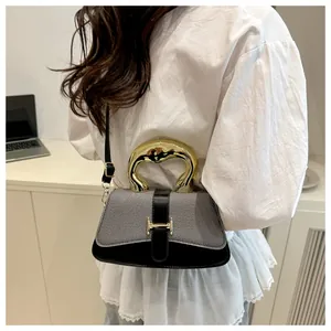 Detail view of the elegant golden irregular metal handle on a luxury tweed crossbody bag