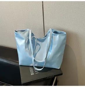 Dettaglio borsa tote azzurra in similpelle con sottili spalline doppie su divano