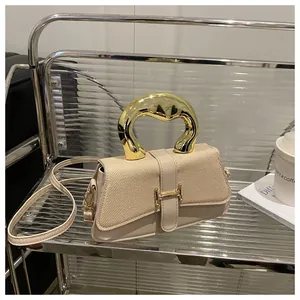 Detail of cream woven bag featuring a bold gold round handle and H-shaped buckle