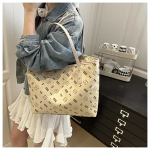 Detail of cream tote bag with bear print and golden rivets worn by model in casual style