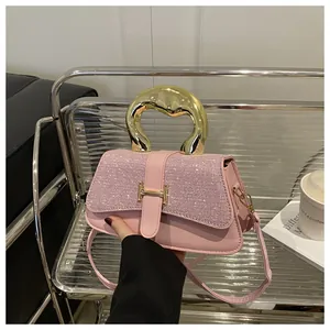 Close-up of pink luxury handbag with shimmering crystals and gold H-shaped buckle detail