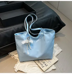 Dettaglio della borsa tote azzurra con ciondolo a fiocco in pizzo bianco e perle