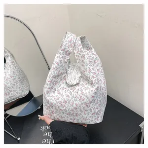 Close-up of floral fabric handbag featuring white lace edges and soft cotton texture
