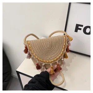 Détail du sac de selle ethnique fait main avec pompons colorés et bandoulière tissée chic