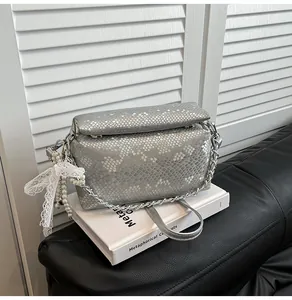 Close-up of silver snakeskin box bag with lace bow and pearl chain detail