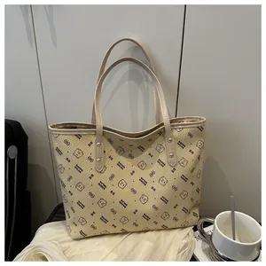 Detail of beige tote bag featuring bear prints, lychee texture, and sturdy handles