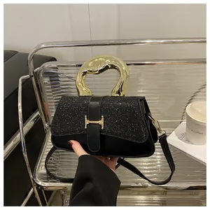 Detailed close-up of a black glitter handbag with unique fluid gold handle and metal buckle